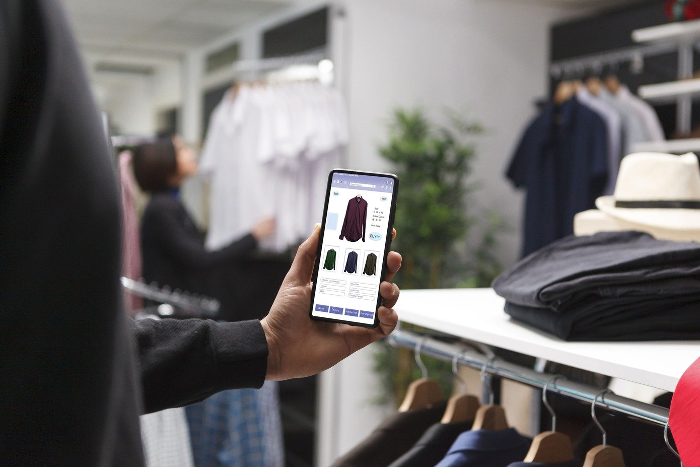 Person browsing AI-personalized clothing recommendations on a mobile shopping app inside a retail store.
